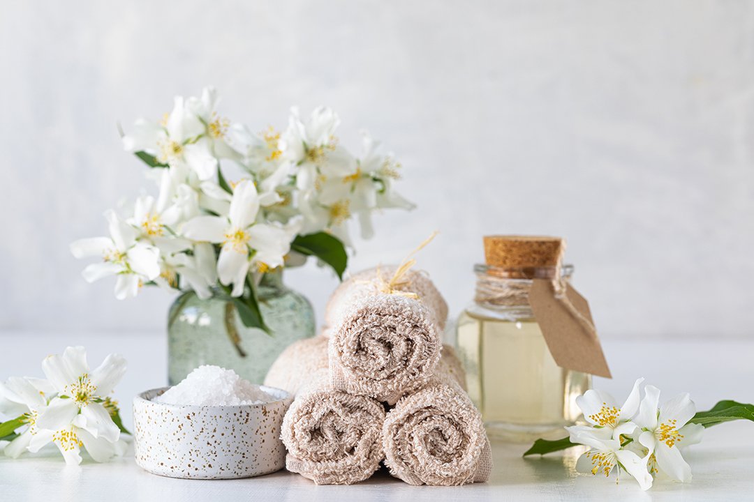 Wellness-Set mit frischen Blumen, Handtüchern, ätherischem Öl und Salz.