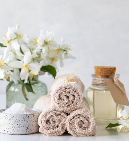 Wellness-Set mit frischen Blumen, Handtüchern, ätherischem Öl und Salz.