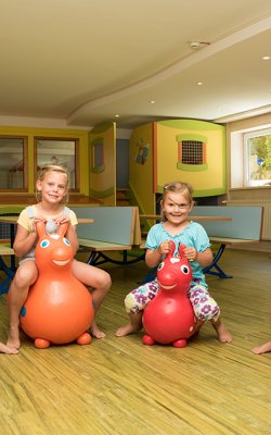 Vier Kinder sitzen auf Hüpfspielzeug, das wie Tiere aussieht.