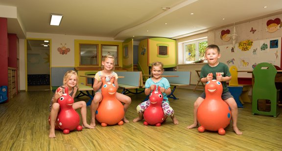 Vier Kinder sitzen auf Hüpfspielzeug, das wie Tiere aussieht.