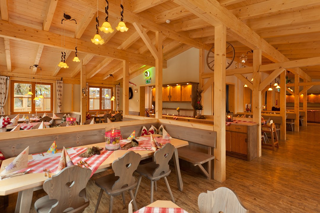 Große Gaststube mit gedeckten Tischen und kompletter Einrichtung aus Holz.