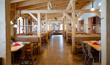 Geräumiger Speisesaal mit Holz-Sitznischen im gemütlichen Alpenstil.