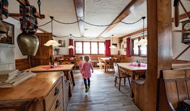 Kinder laufen durch einen Gastraum mit rustikaler Holzeinrichtung.