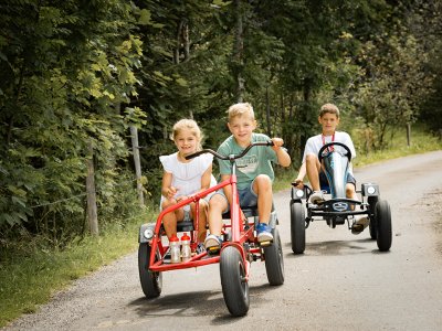 Kinder fahren Gokarts auf einem Waldweg.