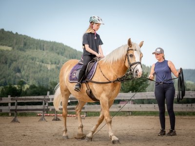 Mädchen beim Reitunterricht, Frau hält die Longe.