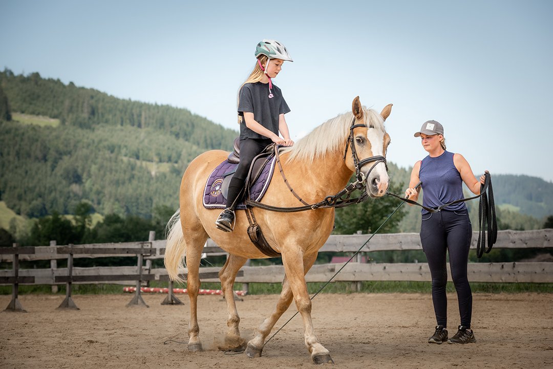 Mädchen beim Reitunterricht, Frau hält die Longe.